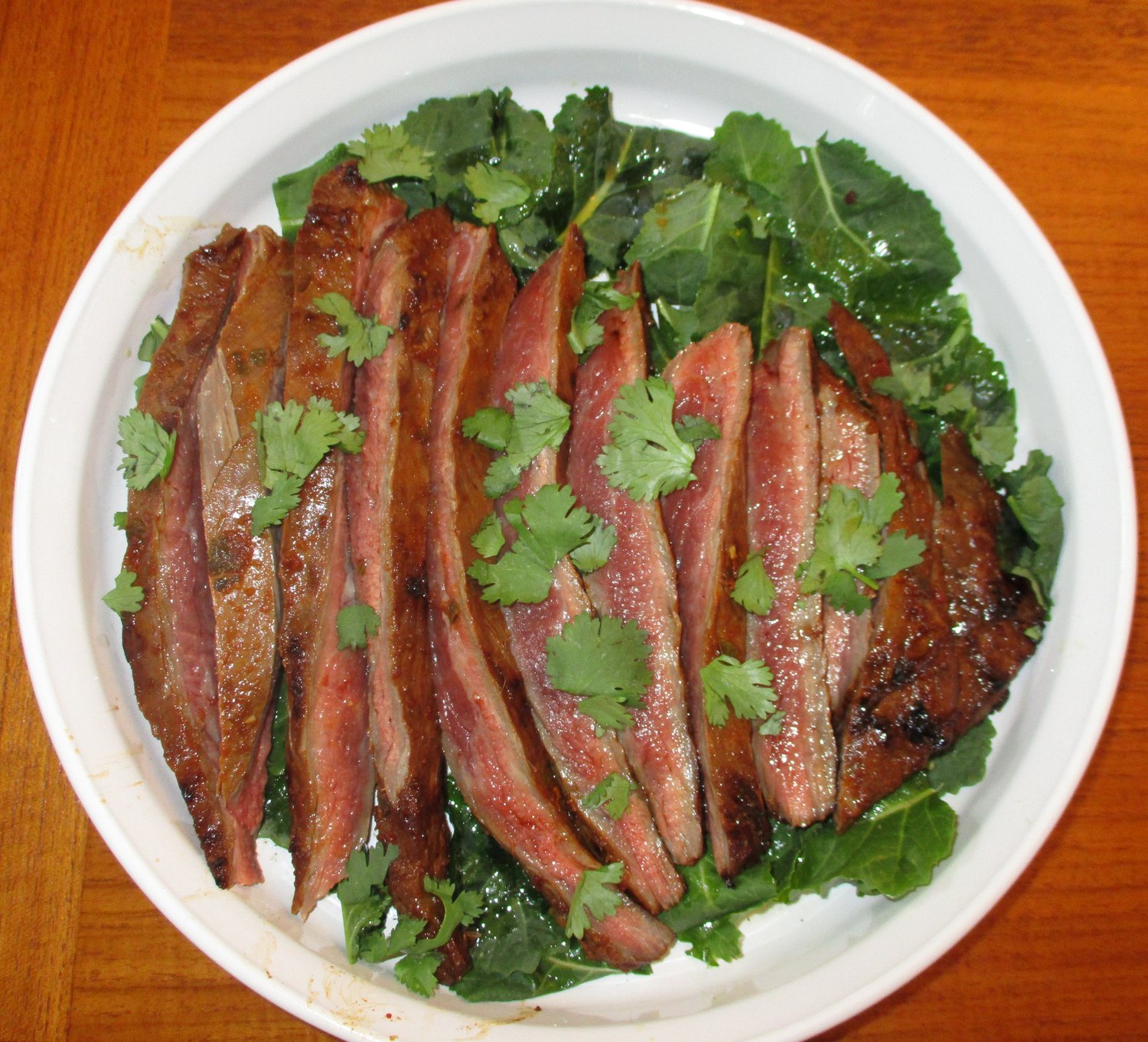 Arrachera served on a bed of baby kale and garnished with cilantro.